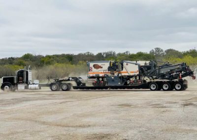 Road milling machine being transported on a flatbed trailer, ready for relocation.